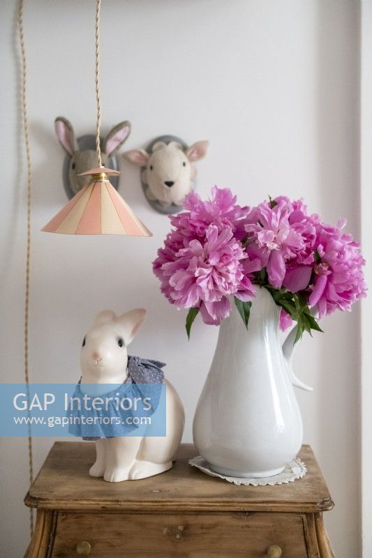 Pink flowers in white vase and animal ornaments in childs bedroom
