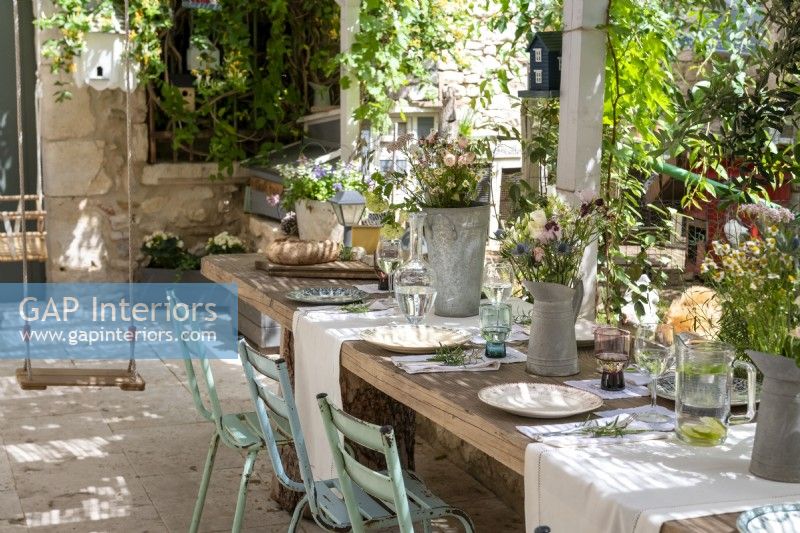 Childs swing next to rustic outdoor dining table laid for lunch 