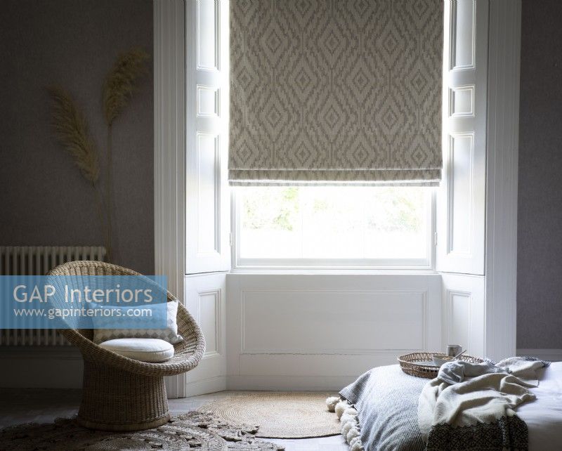 Bedroom with wicker chair and patterned roman blind