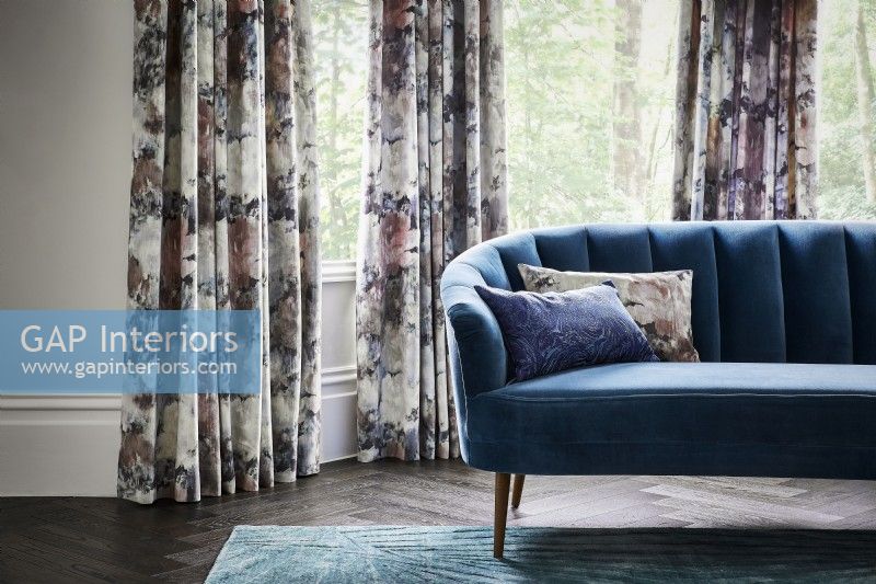 Sofa and cushions in front of patterned curtains