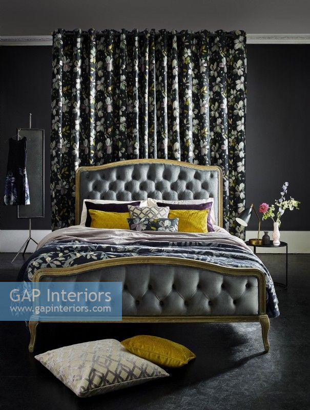 Ornate bed in front of patterned curtains