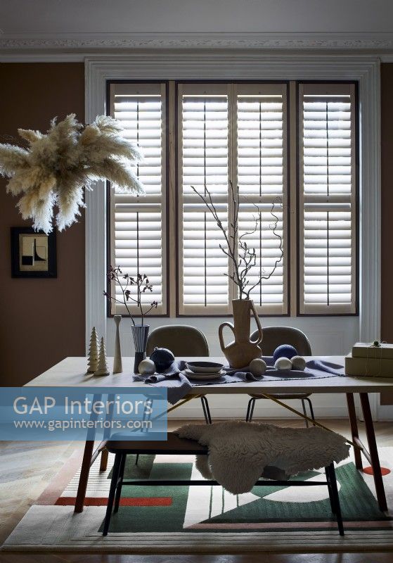 Dining table with ornaments and shutters at window