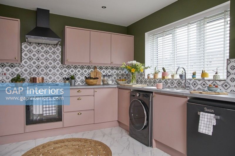 Kitchen with pink cabinets, green walls and patterned tiles.