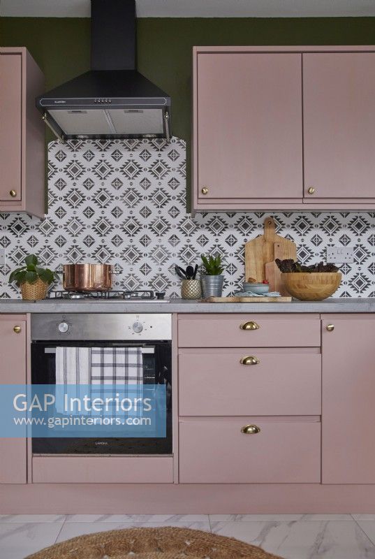 Kitchen detail with oven, pink cabinets and patterned tiles.