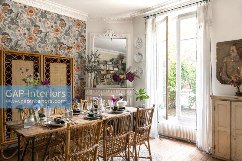 Eclectic dining room with patterned wallpaper and French windows