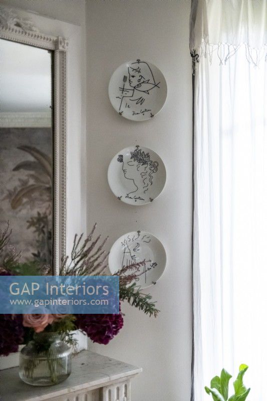 Display of wall mounted decorative plates next to mirror