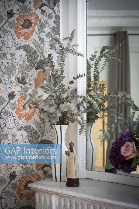 Flower arrangement and floral wallpaper next to mirror - detail