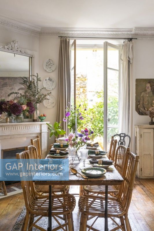 Dining table next to open French windows in retro style dining room