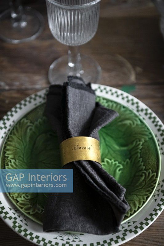 Gold napkin ring on serviette - vintage plates on dining table