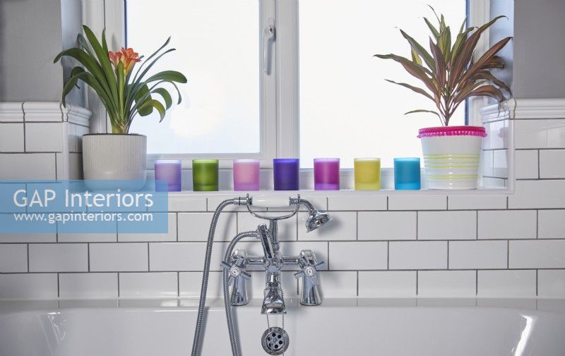 Bathroom detail with white metro tiles and colourful candles on the window shelf.