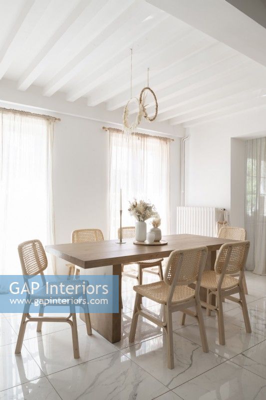 White dining room wtih pale wooden furniture
