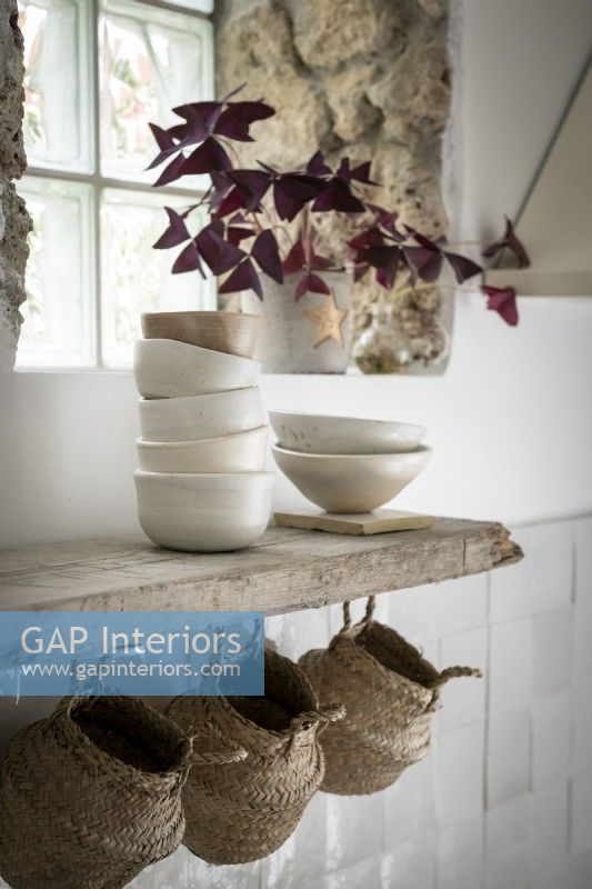 Bowls and baskets on rustic shelf in white country kitchen