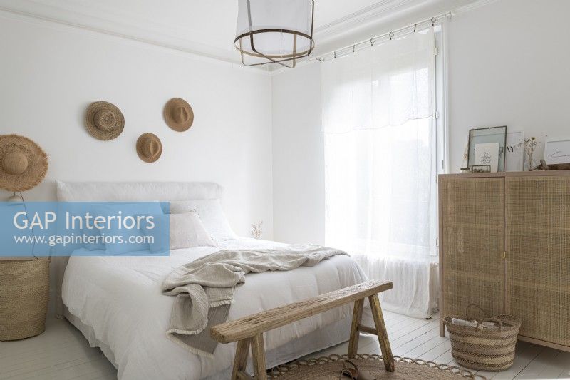 White painted bedroom with wooden and rattan furniture