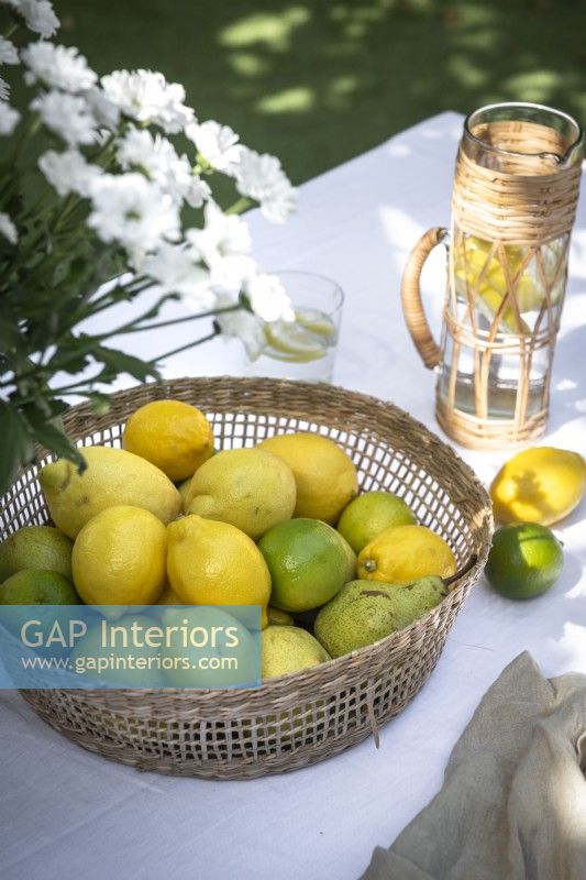 Lemons and limes in a basket on outdoor dining table