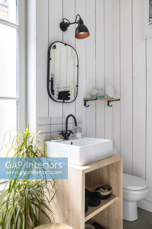 Small sink unit and mirror in bathroom with white wooden walls