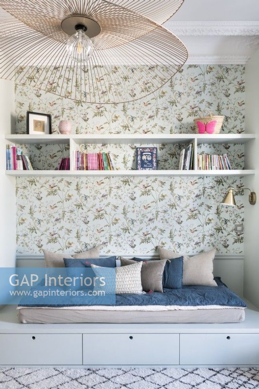 Built-in daybed next to floral wallpapered feature wall
