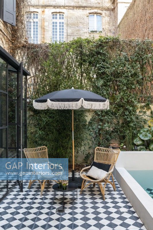 Wicker chairs and black and white parasol by pool 
