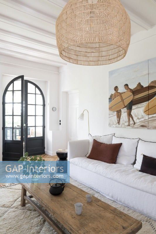 Painting of surfers on wall above sofa in modern country living room