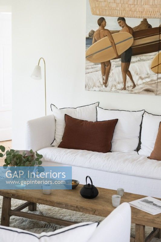 Coastal painting of surfers over sofa in living room