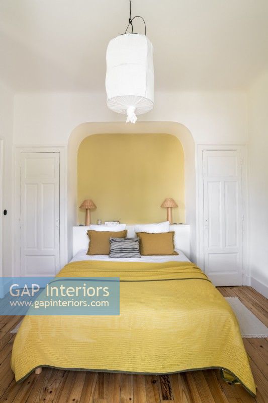Yellow painted alcove around head of bed with yellow bedding