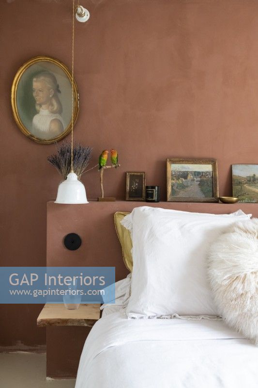 Brown painted wall and headboard with vintage portrait in bedroom