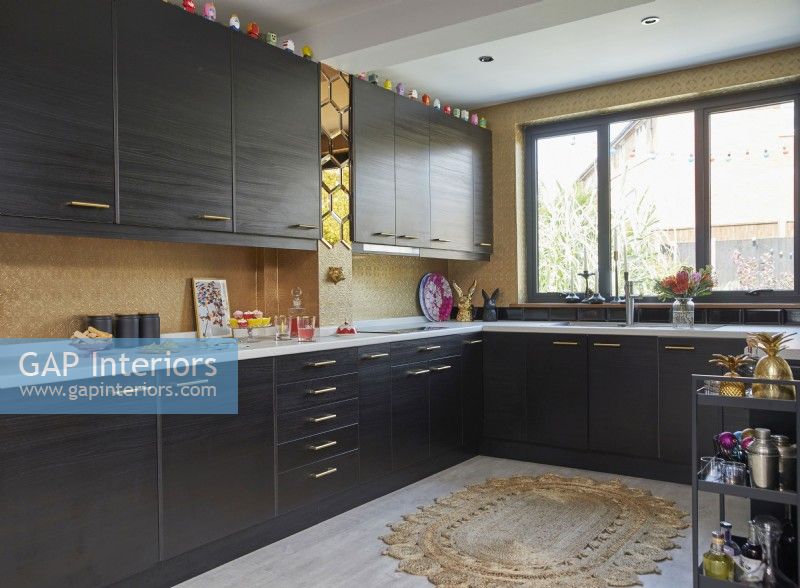 Kitchen with dark brown cabinets, gold wallpaper and mirror tiles.
