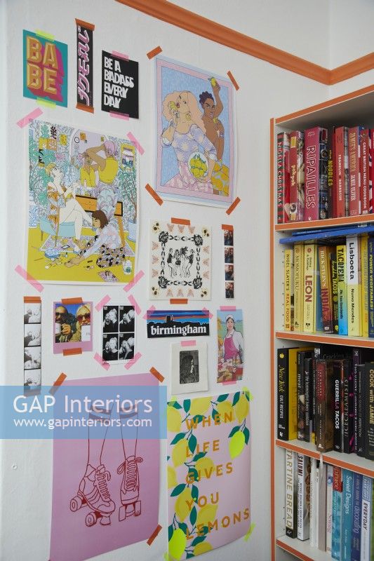 Colourful home office detail with prints, illustrations and a colour coded book shelf.