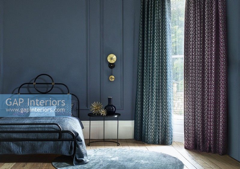 Dark blue bedroom with tall window and curtains