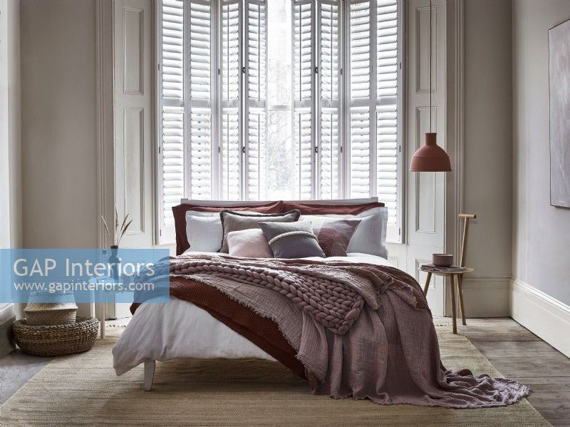 Relaxed modern bedroom with white shutters cracked open