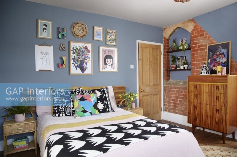 Bedroom with original exposed brickwork, blue painted walls and retro furniture.