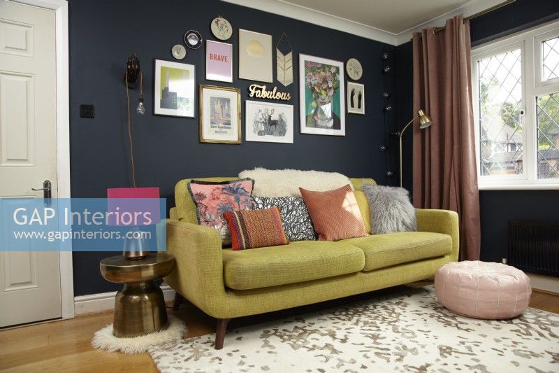 Living Room with a gallery wall, green sofa and pink pouffe.