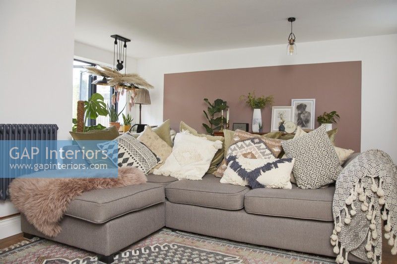 Living room area in an open plan space with a cosy sofa and pink colour blocking on the wall.