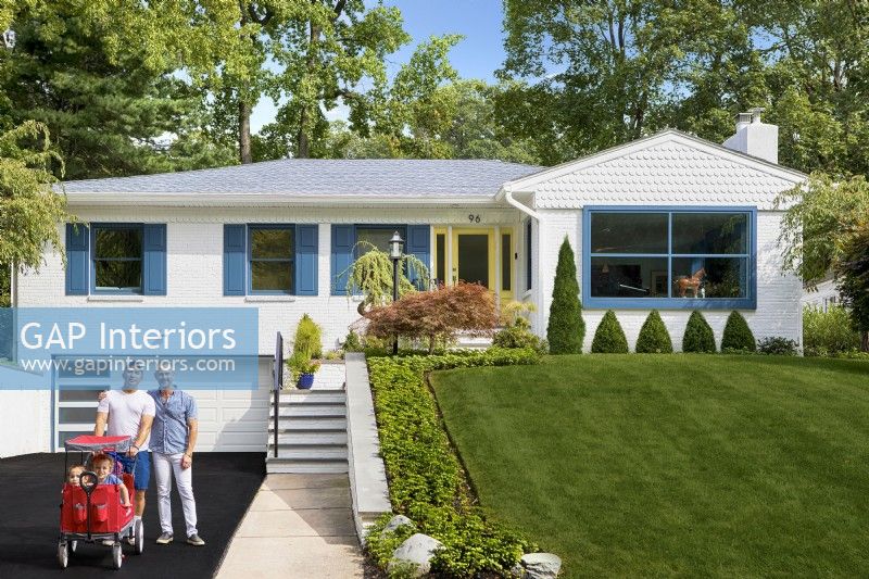 White single story mid century modern brick family home with blue shutters and green lawn.