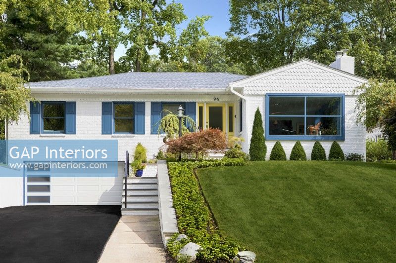 White single story mid century modern brick family home with blue shutters and green lawn