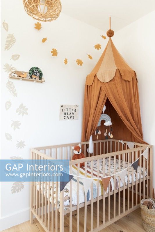 Childs bedroom with wooden cot and canopy tent and wall stencils