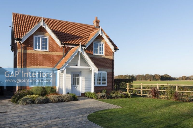 Modern brick new build house with clapperboard porch and paved driveway