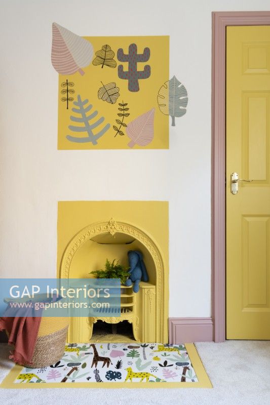 Yellow painted Victorian fireplace in a child's bedroom with vinyl covered hearth and stenciled wall artwork