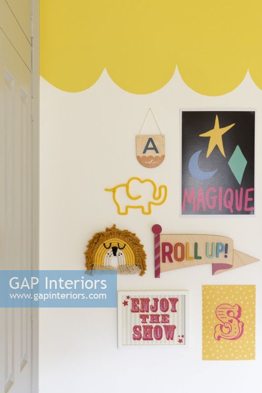 Detail of gallery wall in a child's bedroom with yellow scalloped painted ceiling