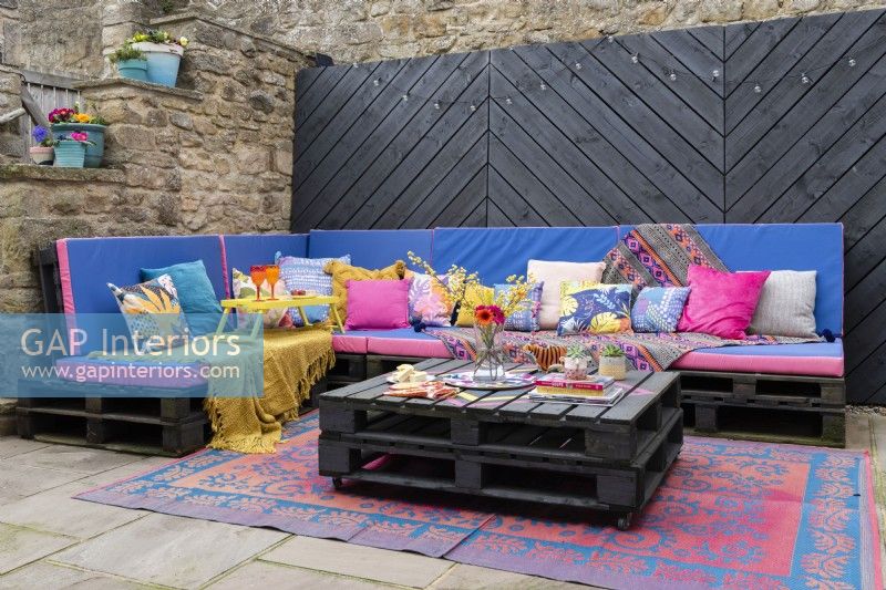 Outdoor entertainment terrace with painted wooden pallets made into seating and table
