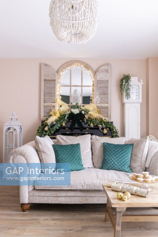 Pale pink sofa in a modern pink living room with a shutter mirror and piano behind