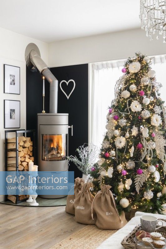 Grey cylinder log burning stove next to a decorated Christmas tree