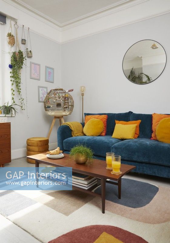 Living room with teal blue sofa, orange and yellow cushions and a retro coffee table.