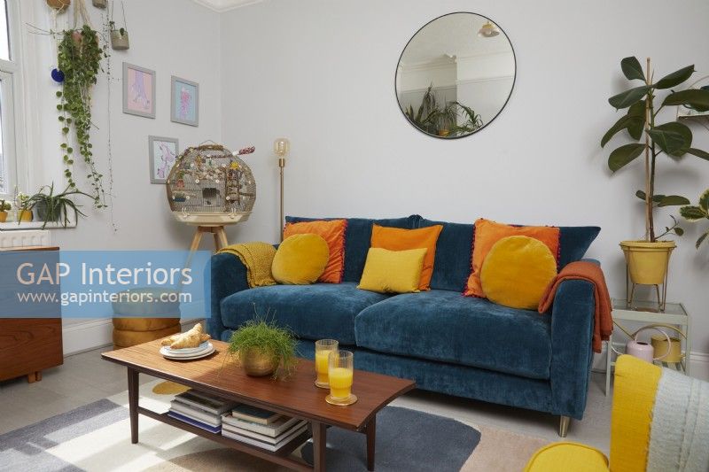 Living room with teal blue sofa, orange and yellow cushions and a retro coffee table.