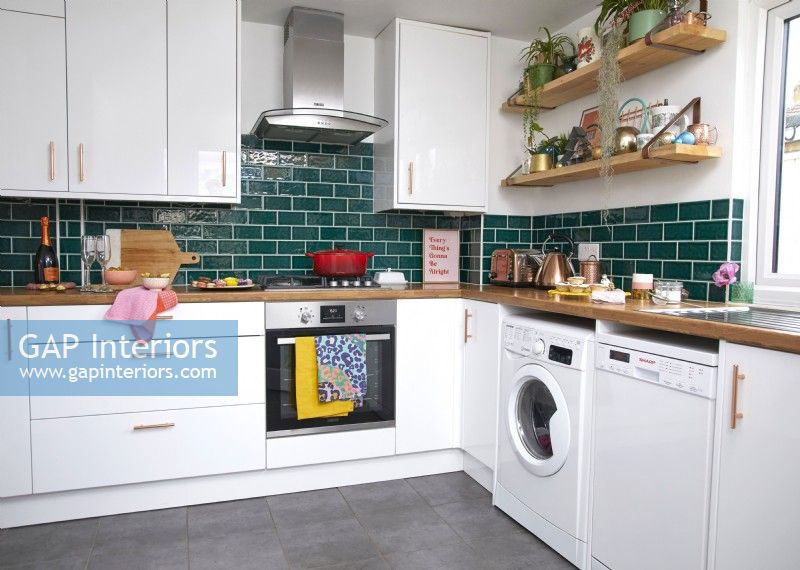 Contemporary kitchen with green metro tiles, open shelving and colourful accessories.
