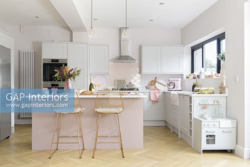 Modern pale pink and white kitchen with island and breakfast bar