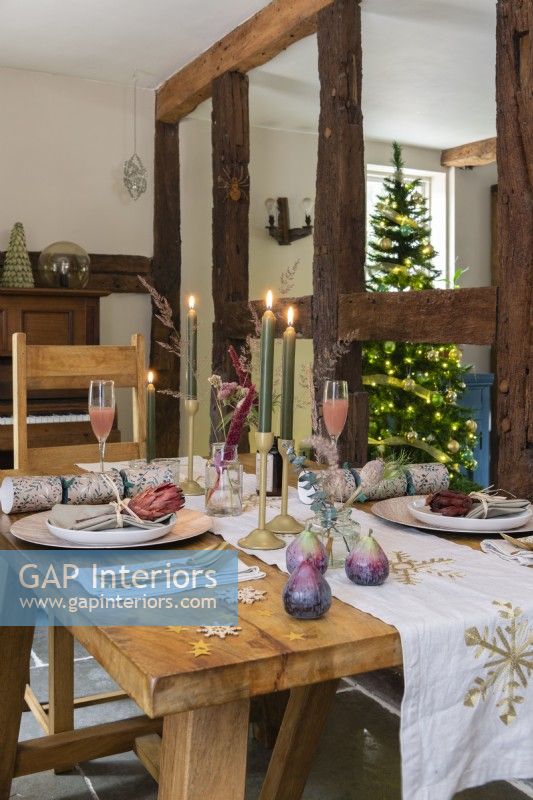 Dining area with wooden dining table laid for Christmas in front of exposed wooden beams