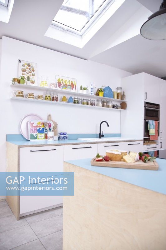 Open plan plywood kitchen with blue worktops and open shelving.