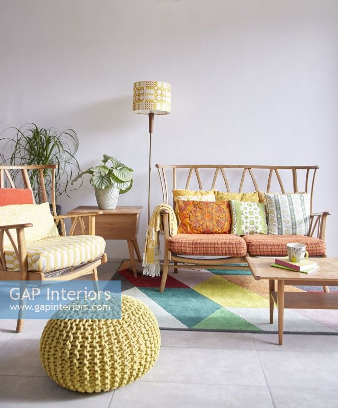 Open plan living area showing a vintage Ercol furniture seating area with retro cushions, a pouffe and a rug.