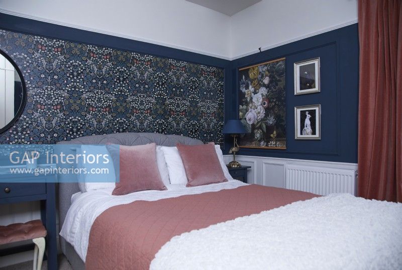 Bedroom with patterned wallpaper and dark blue walls and panelling.