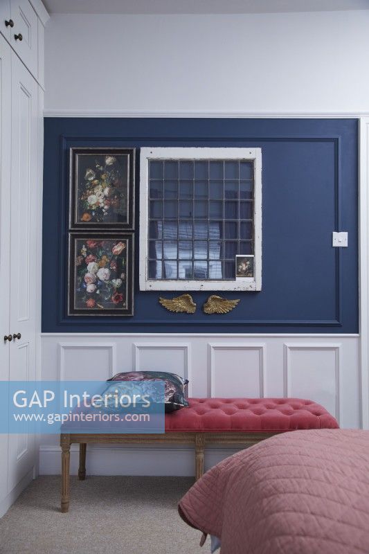 Bedroom detail showing navy blue and white wooden panelling and a coral pink stool.